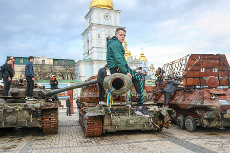 A kid sits on a destroyed tank during an exhibition at Mykhailivs'ka Square in Kyiv. As the full scale invasion of Ukraine by the Russian forces continues, Ukrainian forces still fight Russian troops in the East of their country.
