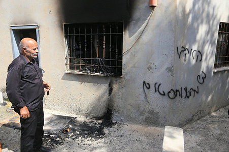 A Palestinian man stands next to Hebrew graffiti and fire damaged window at a mosque in the village of al-Bazariya. The mosque was targeted in an arson attack by Jewish settlers, who sprayed paint on it, and also wrote Hebrew slogans on its walls. Police and the army have opened an investigation on this attack.