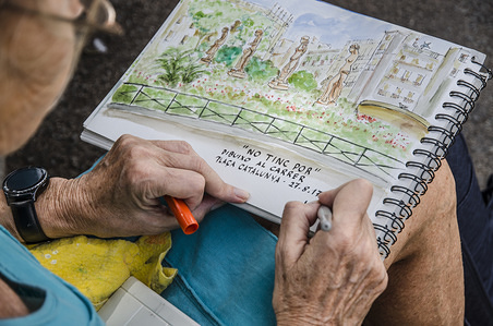 A woman completes her drawing with the inscription quoting "I am not afraid, drawing on the street."
Barcelona Urban Sketchers pay homage to the victims of the terrorist attack of Barcelona and Cambrils under the slogan "I am not afraid. Drawing on the street".