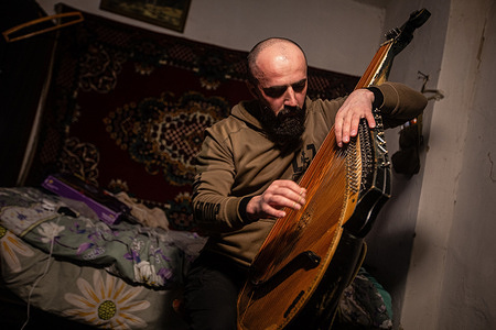 A member of the Cultural Forces plays the bandura in a house for Ukrainian soldiers near the front line. A music recital initiative is led by Cultural Forces, a platform founded by Ukrainian military personnel, artists, and volunteers that brings music and cultural support to soldiers on the front lines.