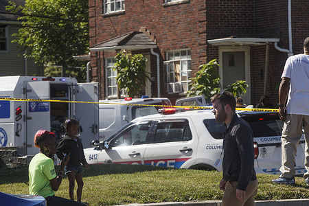 A woman sits with her child behind police tape watching the investigation unfold. 
A police involved shooting occurred near the intersection of Cleveland Ave. and E. 21st Ave. in Columbus, Ohio. Columbus Police report that no one was killed in the shooting, but the Ohio Bureau of Criminal Investigations was called to investigate the shooting.