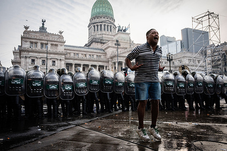 A demonstrator jumps and chants in front of the police line preventing them from advancing toward the National Congress as they protest outside while the Senate debates Javier Milei's Ley Bases. The Senate Chamber of the Argentine Congress is debating Javier Milei's Ley Bases, which has already passed the Chamber of Deputies. Meanwhile, hundreds of thousands of demonstrators are protesting in the streets, leading to confrontations and repressive actions by security forces.