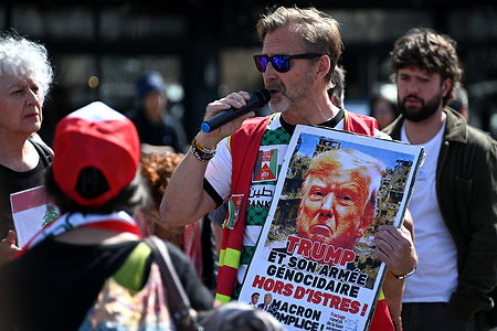 A protester gives a speech while holding a placard against Donald Trump with a portrait of the American president during a demonstration in support of Lebanon. People demonstrate in Marseille to demand a ceasefire and peace in Lebanon.
