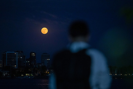 A full moon seen with a person standing on Moda beach. The full moon appearing in the evening hours in Istanbul created beautiful images on the Moda beach.