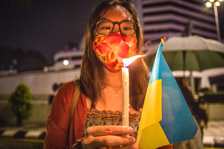 A Ukrainian supporter holds a Ukrainian flag and a burning candle in solidarity with Ukraine during the 'Stand for Ukraine Anti-War rally' in Merdeka Square, Kuala Lumpur.