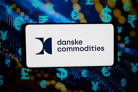 In this photo illustration, the logo of energy trading company Danske Commodities AS is displayed on a smartphone in front of abstract background on computer screen.