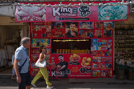 People pass by un fried octopus stall in Chatuchak Market which is one of the best known spots for tourists.