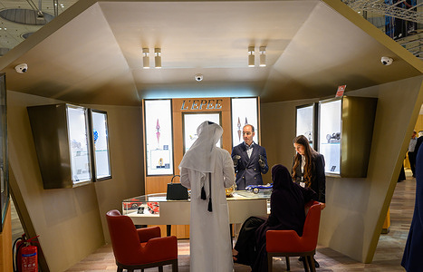 Visitors try on luxury jewelry pieces inside an illuminated display area during the Doha Jewellery and Watches Exhibition (DJWE).The exhibition brings together world-renowned jewellers, luxury watchmakers, and exclusive collections.
