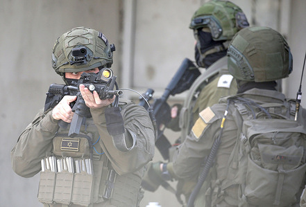An Israeli soldier points his weapon at Palestinians to prevent them from entering a market during a security operation in Balata refugee camp, east of Nablus. Israeli forces entered the market and closed the camp's entrance. Soldiers also raided shops, arrested residents, and interrogated them about the security situation in Balata camp.