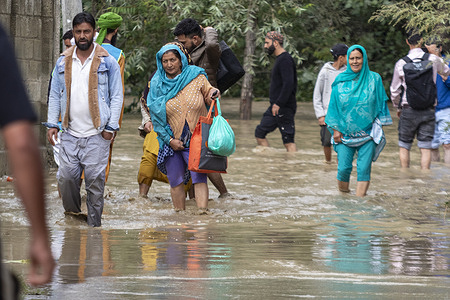 People wade through a flooded road on the outskirts of Srinagar. An imminent flood threat looms over Jammu and Kashmir as rivers and streams swell after continuous rainfall. Authorities have closed all schools and shut the Srinagar-Jammu national highway, the only road link connecting the Kashmir Valley with the rest of India. The local meteorological department forecasts heavy to very heavy rain in the next 24 hours. Residents have been urged to stay vigilant and take precautions due to the heightened risk of landslides and floods.