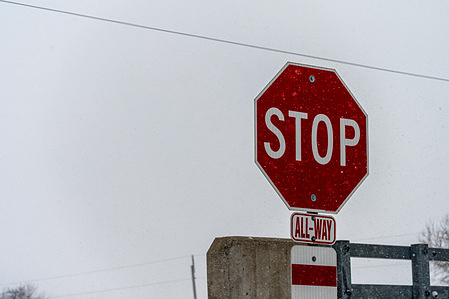 'Stop' road sign seen displayed. A major winter snowstorm brings blowing snow, blustery conditions and very low temperatures to parts of the United States and Canada. The cold intensified the storm’s impacts, reducing visibility and creating hazardous travel as people went about their day, while snowplows worked to clear local roads amid accumulating snow, strong winds and frigid air.