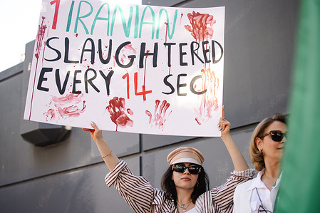 A woman holds a sign reading “1 Iranian Slaughtered Every 14 Sec” during a solidarity march supporting the people of Iran. The demonstration began at Los Angeles City Hall in downtown Los Angeles, where protesters gathered as part of a global action highlighting ongoing human rights abuses in Iran and calling for international awareness and accountability.