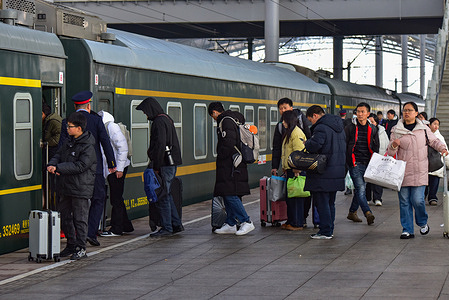 Passengers board a green train at Fuyang Railway Station, carrying their luggage as part of the Spring Festival travel rush. Each year, millions of people working, studying or living away from their hometowns return home to celebrate Spring Festival, China's most important traditional holiday, forming the world's largest annual human migration.
