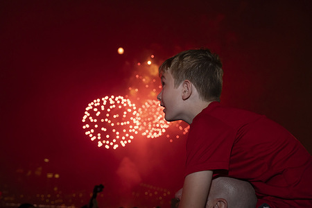 A child sits on his father's shoulders as they watch fireworks explode over the Brooklyn Bridge and downtown Manhattan skyline during Macy's fireworks display celebrating the United States' 249th independence day at Brooklyn Bridge Park.