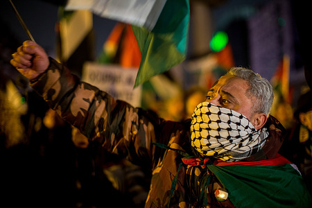 A protester shouts with his face covered by a keffiyeh during a rally outside the Movistar Arena, where the Euroleague basketball game between Real Madrid and Maccabi Tel Aviv is being held behind closed doors.
