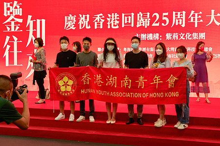 A group of people poses for a photo at an exhibit celebrating the 25th anniversary of returning to the homeland in Hong Kong's Wan Chai district.