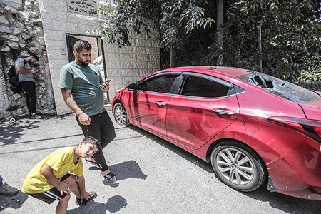 Palestinians inspect a damaged car, after it was ambushed by Israeli forces and all its passengers were arrested, near the city of Nablus in the northern occupied West Bank.