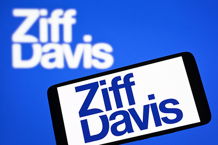 In this photo illustration, the Ziff Davis logo is seen on a smartphone and in the background.
