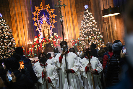 The altar servers perform the entrance procession along the church aisle during the Christmas Eve mass at Saint Antuan Church.