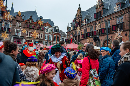 Hundreds of families are seen attending St. Nicholas's speech. In Nijmegen, Sinterklaas (St. Nicholas) entered the city center along a route, accompanied by his helpers, the Pieten (Peters), who gave traditional candies to children and adults. On the first Saturday after November 11th, the red-and-white-clad Sinterklaas (St. Nicholas) arrives in several Dutch cities.