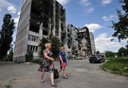 Women walk past a residential area damaged by the shelling of the Russian army in the city of Borodyanka, northwest of the Ukrainian capital Kyiv.