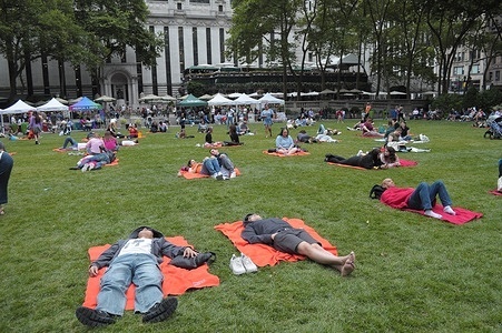 People lie down on blankets on the field in Bryant Park, Manhattan, New York City.