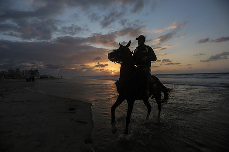Palestinian man rides his horse along the beach at sunset in Gaza City.