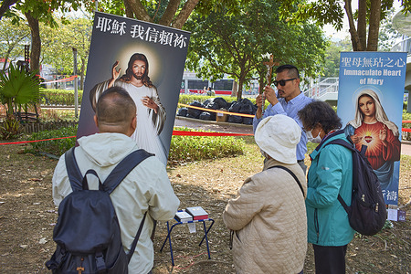 A Catholic priest and Catholic faithful pray in tribute to the victims of the fire. A massive fire at the Wang Fuk Court residential complex in Tai Po, which killed 159 people and destroyed seven of its eight towers, has prompted thousands of Hong Kong residents to gather at the site to mourn and pay tribute. Mourners have built a large makeshift memorial with flowers, notes, and offerings, while the wider community has mobilized donations to support the many displaced families. The tragedy, fueled by unsafe renovation materials, is now considered one of Hong Kong’s deadliest disasters in decades.