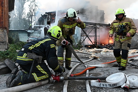 Firefighters work near the scene of a fire after a jet-powered drone struck an office building in Kyiv's Podilskyi district. The Russian army struck offices in Kyiv's Podilskyi district, destroying the facility and civilian vehicles.