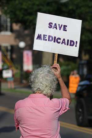 A woman holds a placard during the "Good Trouble Lives On: Dying for Healthcare" rally at Danville's Memorial Park. The event was one of hundreds of anti-Trump protests held across the United States on the fifth anniversary of the death of civil rights leader and Georgia Congressman John Lewis.