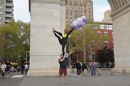 A pair performs partner acrobatics in Washington Square Park, Manhattan, New York City.