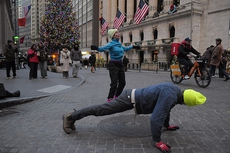 Street performers dance on the street in front of the New York Stock Exchange in the Financial District in Manhattan, New York City.