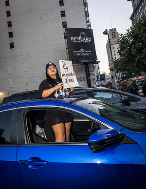 A female protester with a placard stands in car during the fifth day of protests against ICE. U.S. Immigration and Customs Enforcement (I.C.E.), Get Out Of Los Angeles protest in Downtown Los Angeles, where protestors gather to demand that I.C.E. agents stop detaining and arresting migrants.