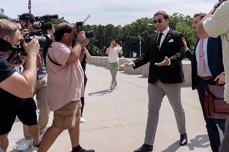 George Santos (Center, Right), former Representative from New York, escorted through members of the press by council Andrew Mancilla (R) arrives at federal court in Central Islip. Santos is expected to plead guilty to fraud and money laundering charges to avoid trial and possible jail time.