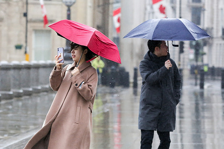 People shelter under their umbrellas during rainfall in central London.