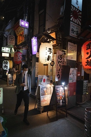 A businessman wearing a facemask as a precaution against the spread of covid-19 seen walking through a side alley in Shimbashi district.