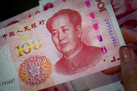 In this photo illustration, the hand seen holding several banknotes of Chinese currency, renminbi, with a face value of one hundred yuan.
