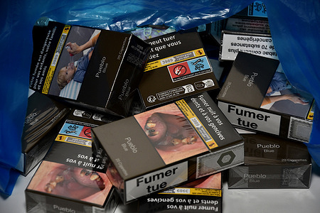 In this photo illustration, loose packets of cigarettes come out of a blue plastic bag. From January 1, 2024, most packs of 20 cigarettes will cross the symbolic bar of 12 euros.