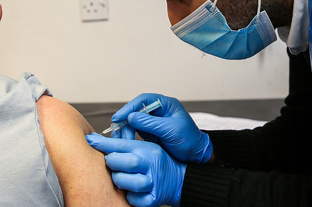 A Covid-19 vaccinator administers the Oxford/AstraZeneca vaccine to a member of public at a vaccination centre in London.