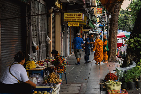 A view of Buddhist monks receiving morning alms from the lay community, part of a daily ritual in public urban space.
Each morning in Bangkok, Buddhist monks walk the streets to collect alms, offerings of food and flowers, from local residents. The practice is a vital part of Theravada Buddhist tradition, symbolizing generosity and spiritual connection.