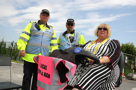 a disabled Anti-Frack Protester on a Mobility Scooter, watched by Two Police Liaison Officers attempts to block the gates of the Fracking company "Cuadrilla's" Frack site during a quiet day of continuing protests. Cuadrilla have applied for an extension and modification of an injunction to make protesting at their site illegal.