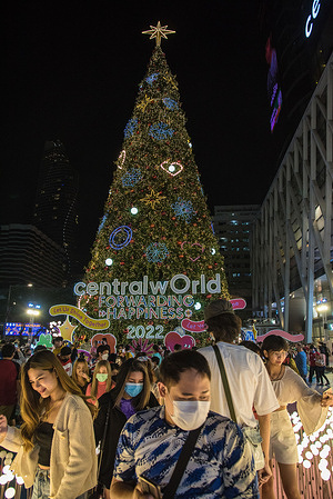 People stand in front of a huge Christmas tree decorated ahead of the Christmas and New Year season outside Central World the shopping mall in Bangkok.
