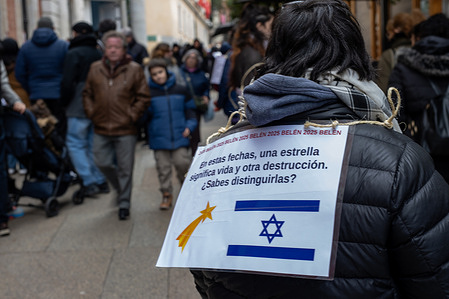 A protester carries a placard with messages against Israel during the demonstration. Pro-Palestinian activists held a protest to condemn the genocide perpetrated by Israel in Palestine, consisting of forming a parallel line at the entrance to the Nativity scenes displayed by the Community of Madrid at the Royal Post Office, the seat of the regional government.