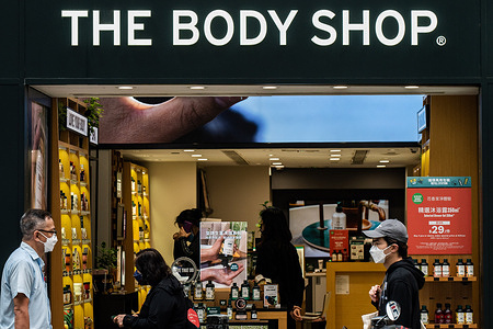 People wearing surgical masks walk by The Body Shop in the Central Business District of Hong Kong. According to the Hong Kong Government's economic analysis, the retail sector is facing immense pressure in the near-term, with the pandemic and associated social distancing measures creating challenges for a revival.