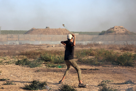 A Palestinian protester uses a slingshot to hurl stones during the demonstration. The Palestinian factions organized demonstrations along the border fence between the Gaza Strip and Israel against Israeli violations in Jerusalem and Al-Aqsa Mosque, coinciding with the Israeli religious holidays that began yesterday evening, Thursday.