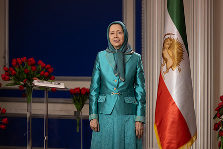 Maryam Rajavi, President-elect of the National Council of Resistance of Iran (NCRI), stands beside the Iranian flag during the Persian New Year (Nowruz) ceremony marking the year 1405, addressing supporters and members of the Iranian Resistance. Iranian expatriates, members of the National Council of Resistance of Iran (NCRI), and families of victims of both the Shah’s regime and the clerical regime gathered for a Persian New Year (Nowruz) ceremony in the presence of Maryam Rajavi, President-elect of the NCRI, marking the beginning of the year 1405. The ceremony highlights calls for the establishment of a democratic republic in Iran based on popular sovereignty, rejecting both monarchical and clerical dictatorship, and emphasizing peace, freedom, justice, gender equality, and a non-nuclear Iran. The event pays tribute to martyrs and political prisoners while underscoring the continued struggle of the Iranian Resistance and reaffirming the NCRI’s Ten-Point Plan as a roadmap toward a free Iran built through the will and vote of its people.