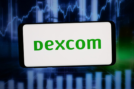 In this photo illustration, the logo of US medical device company DexCom Inc. is seen displayed on a smartphone in front of abstract background on computer screen.