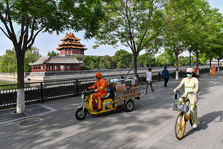 People wearing facemasks as a precaution against the spread of covid-19 seen riding along the roads near the Forbidden City in Beijing.