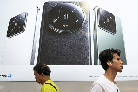 Pedestrians walk past a Xiaomi smartphone advertisement at its flagship store in Hong Kong.