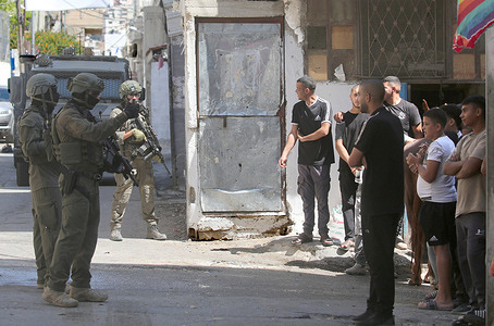 Palestinians argue with Israeli soldiers during a raid on Balata refugee camp, east of Nablus in the West Bank. Israeli military forces raided the central market during a security operation. Soldiers fired tear gas, causing dozens of Palestinians to suffer. Youths threw stones at the soldiers during the operation, and an elderly man was arrested.